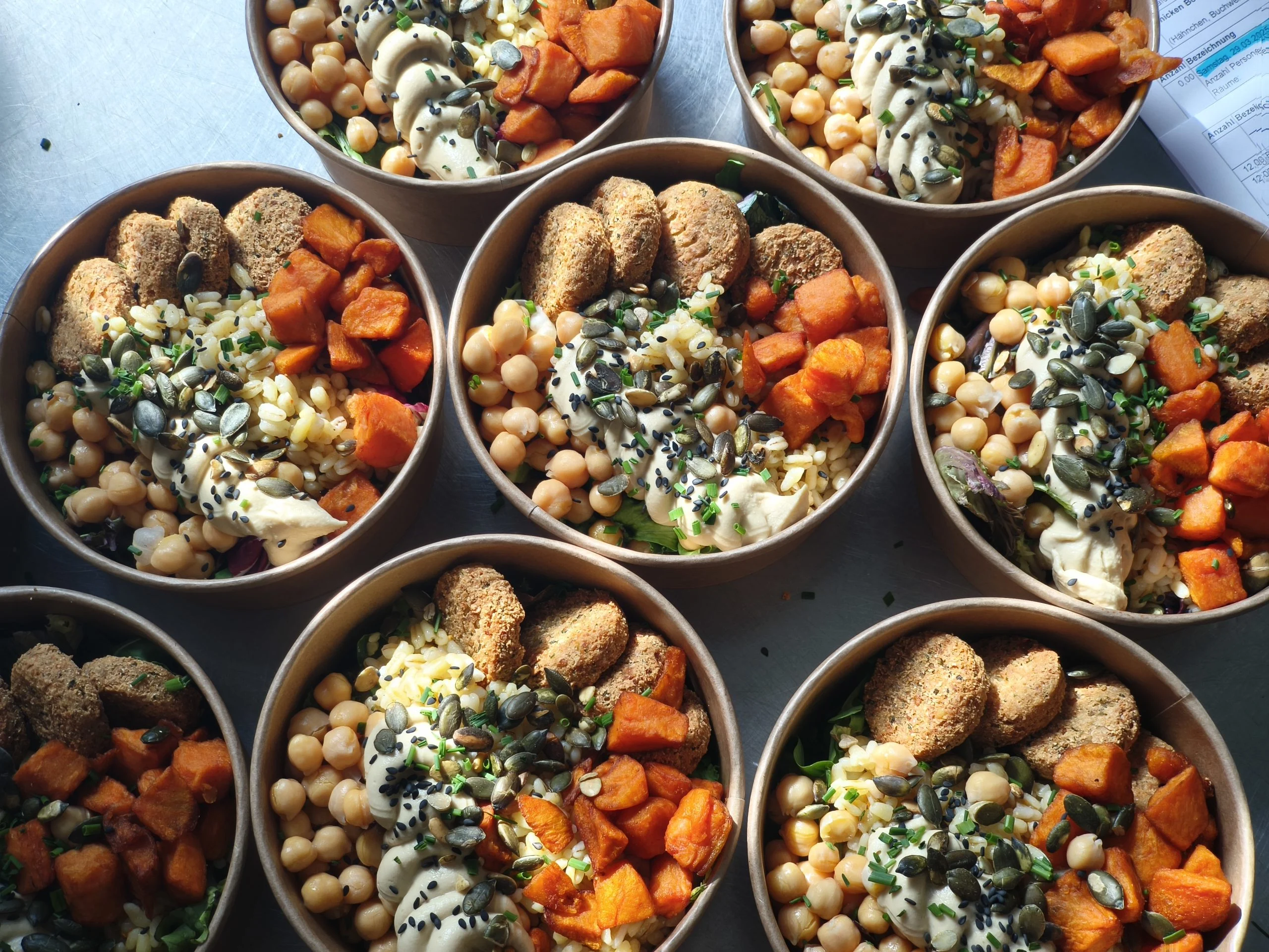 Mehrere Bowls mit Kichererbsen, Süßkartoffeln, Hummus und Granola für ein Catering-Buffet