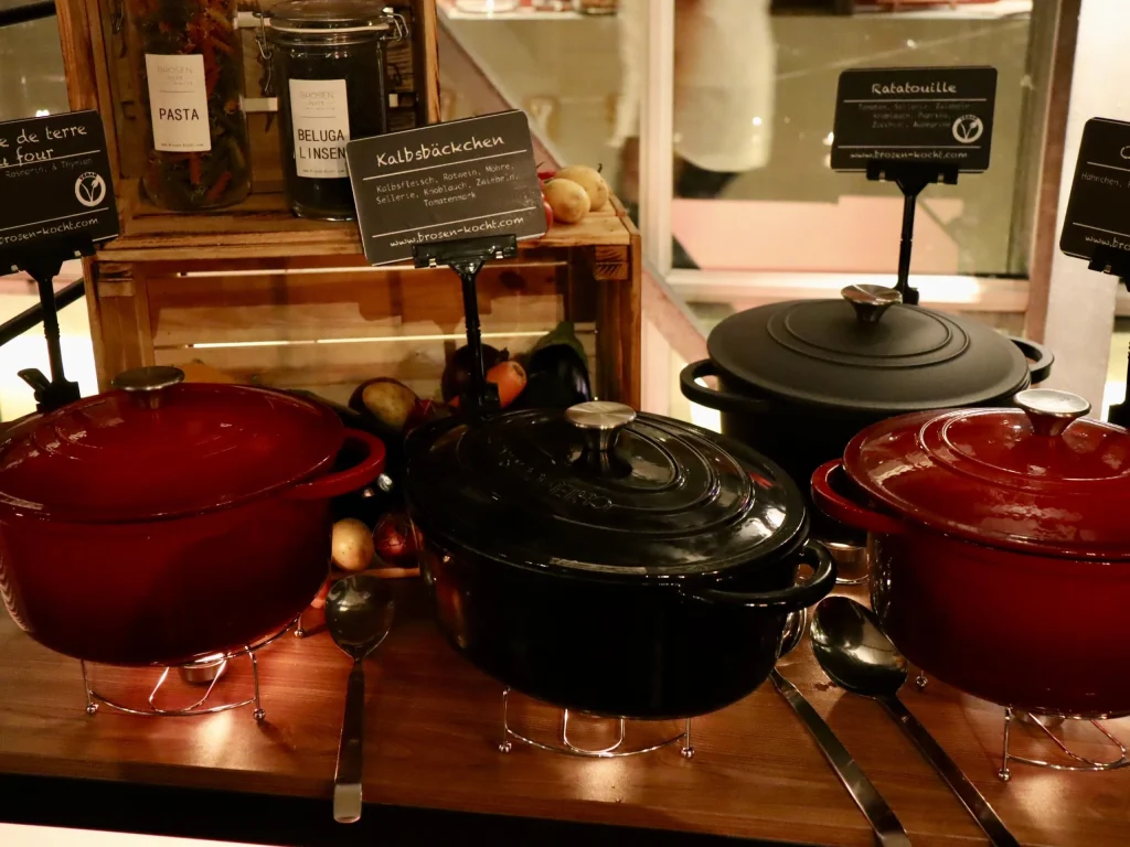 Mehrere Gusseisen-Bräter mit warmen Speisen auf einem Catering-Buffet
