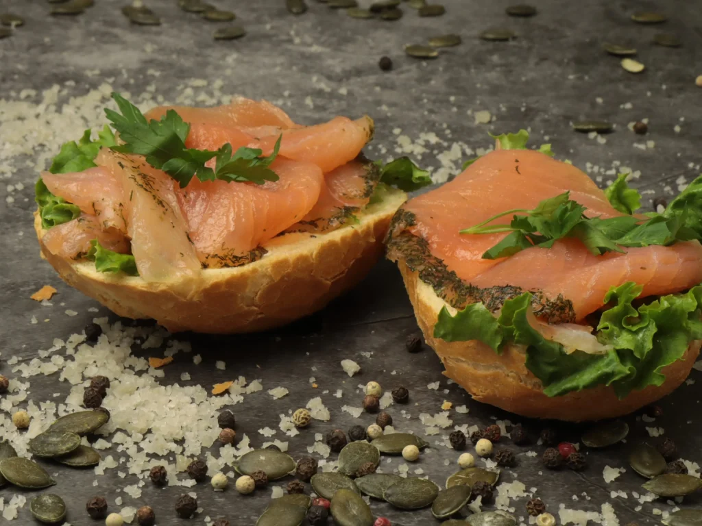 Belegtes Brötchen mit geräuchertem Lachs, Salat und Kräutern als Fingerfood