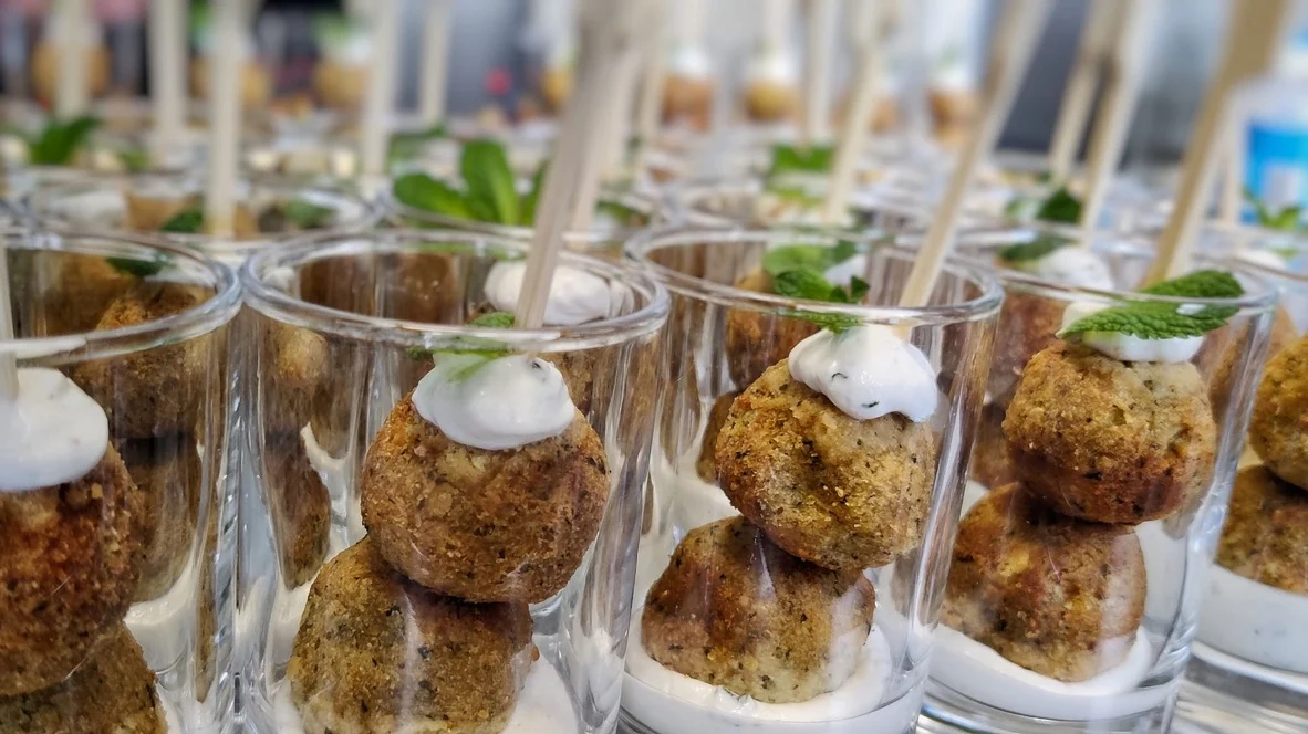 Reihe von Gläsern mit Fingerfood-Häppchen, Dip und Kräuterspieß