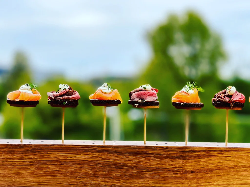 Fingerfood-Spieße mit Lachs und Roastbeef auf einem Holzbrett im Freien
